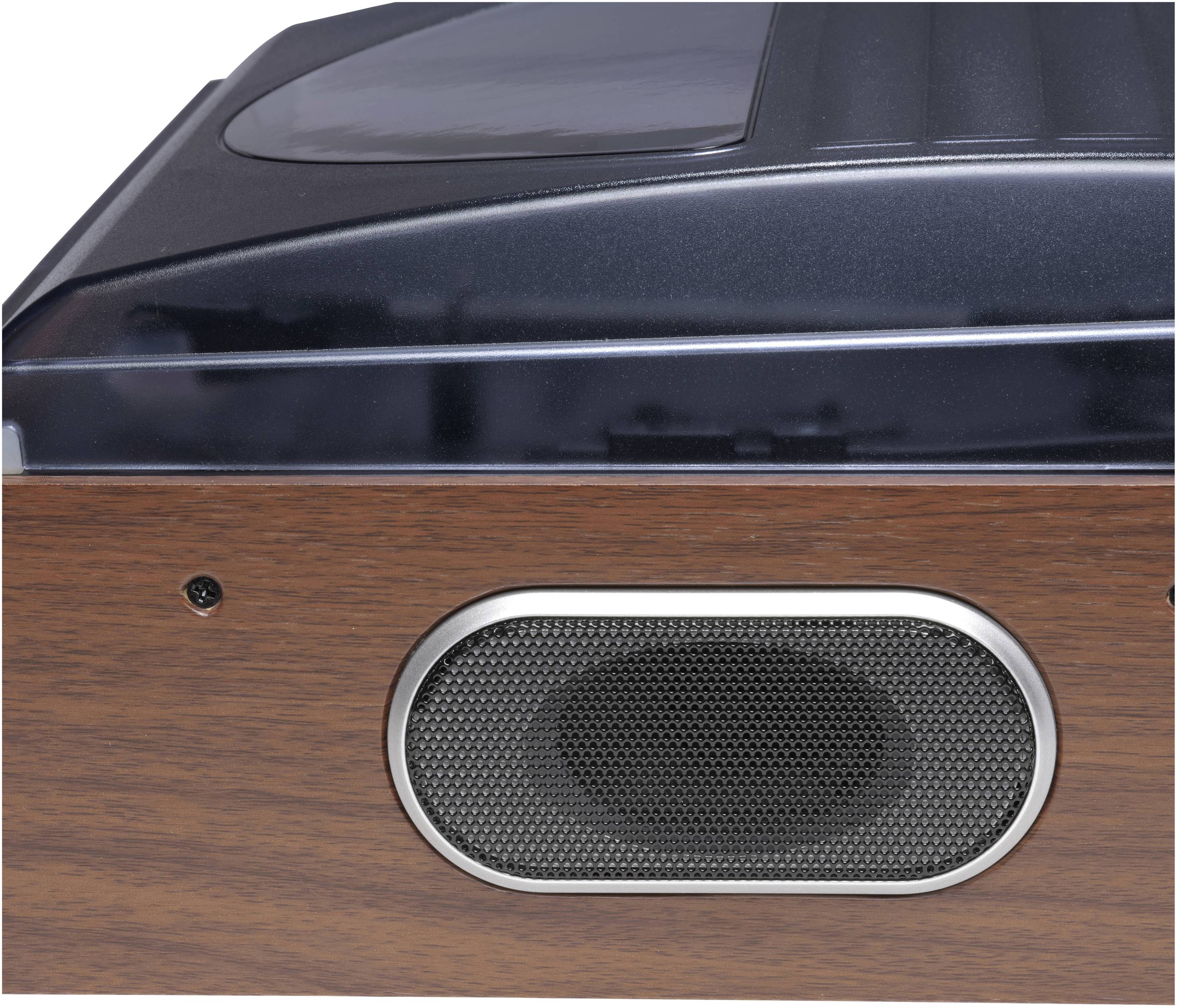 Close-up of a speaker in a wooden music or radio system, with a black speaker grille and a shiny surface on top.