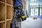 A person is working in an empty room with bookshelves, wearing a tool belt with various tools and accessories.