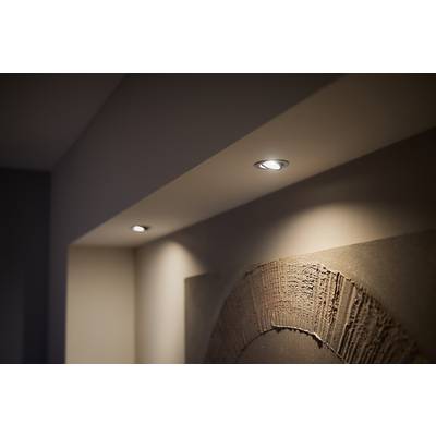 Two recessed spotlights illuminate an artwork on a wall in a modern, minimalist room.