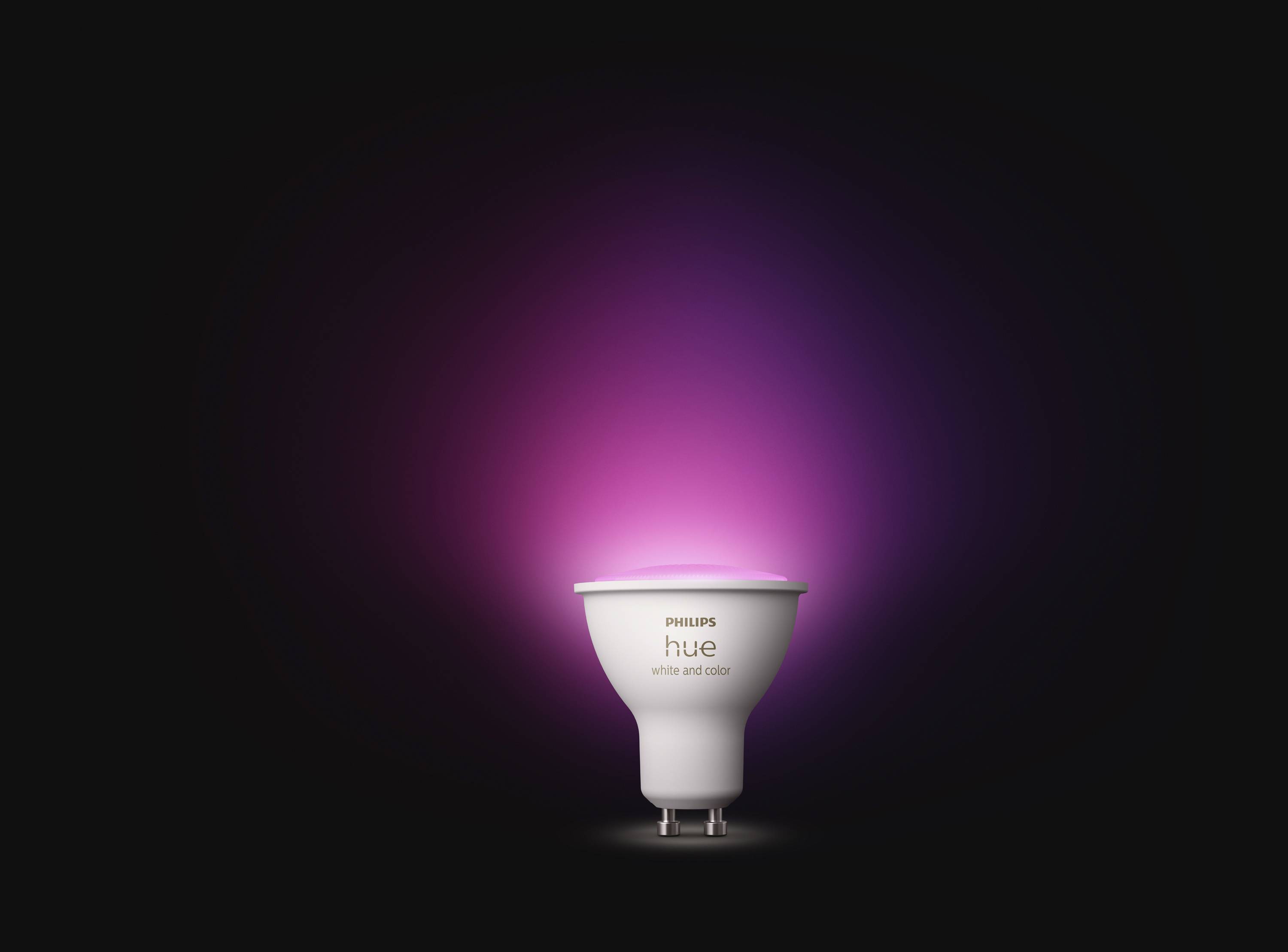 Smart light bulb with a pink light glow against a dark background, product name 'Philips Hue White and Color' visible.