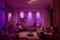 Cosy living room with modern, purple lighting, a large armchair, sofa and decorations on shelves. Relaxed atmosphere.