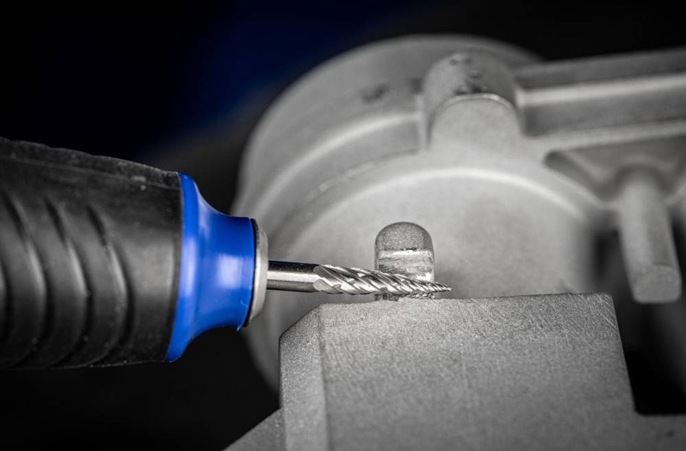 A milling cutter is machining a metal workpiece. A close-up shows the cutter in action, with metal shavings forming at the point of contact.