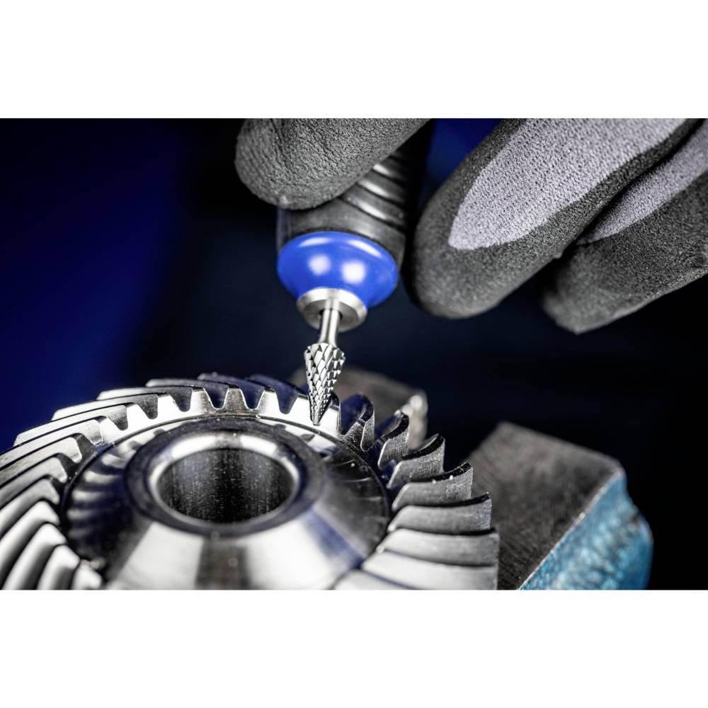 A hand in a glove holds a rotating tool, working a metal gear tooth to form precise edges.