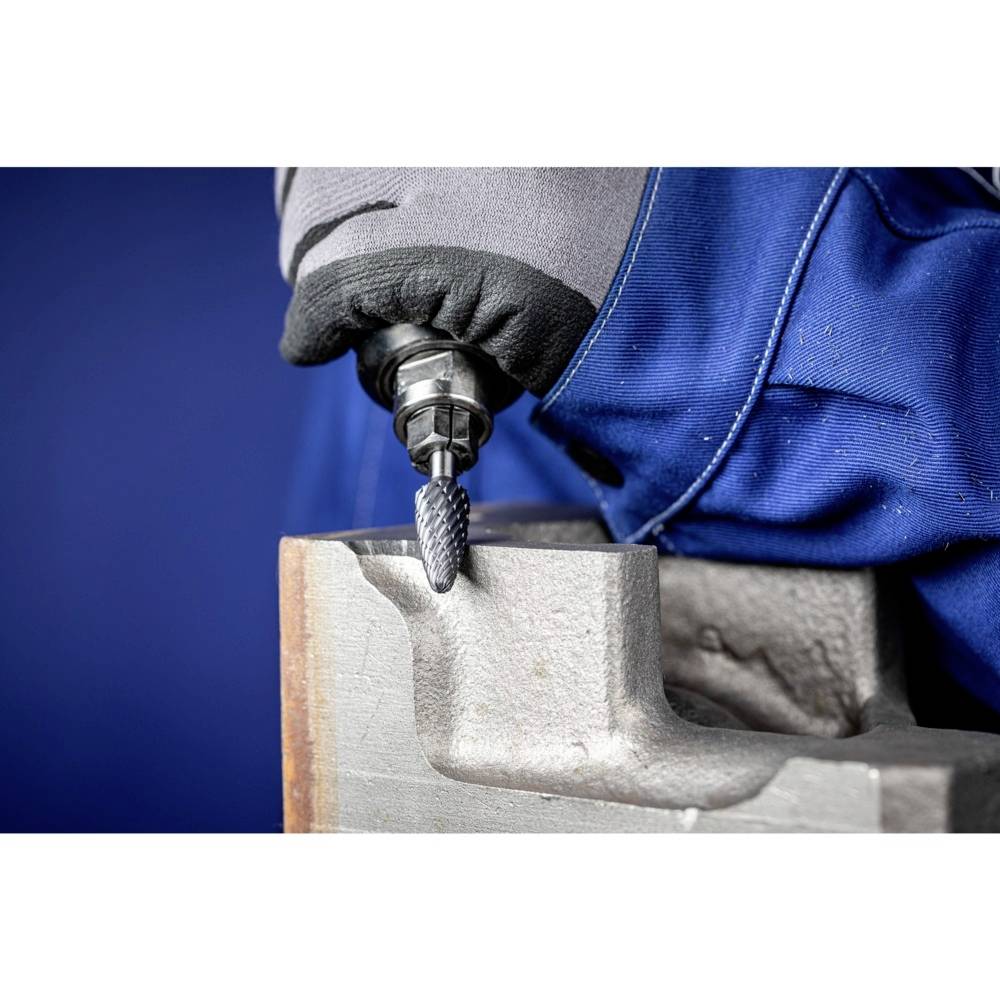 A worker grinds metal with a rotating tool. Close-up of the hand, wearing a grey glove.