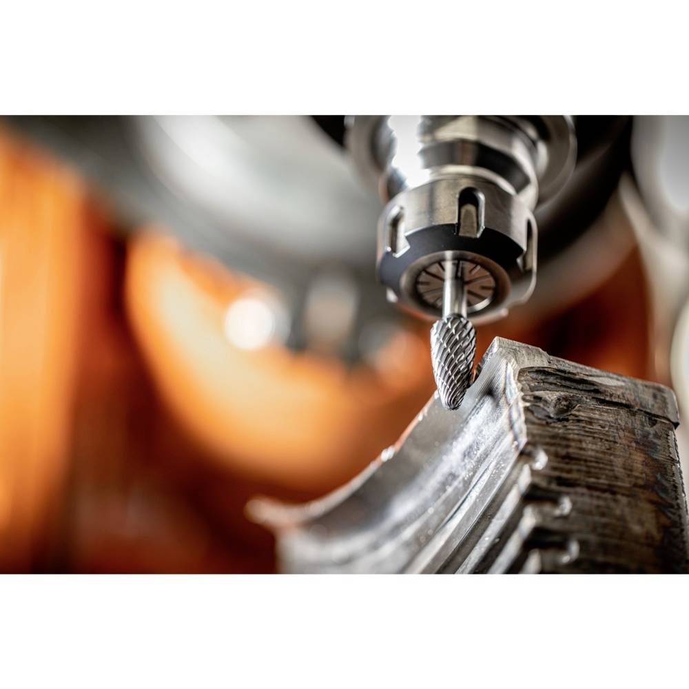 An industrial cutter is machining a metal surface, with sparks flying. The scene depicts precise metalworking in close-up.