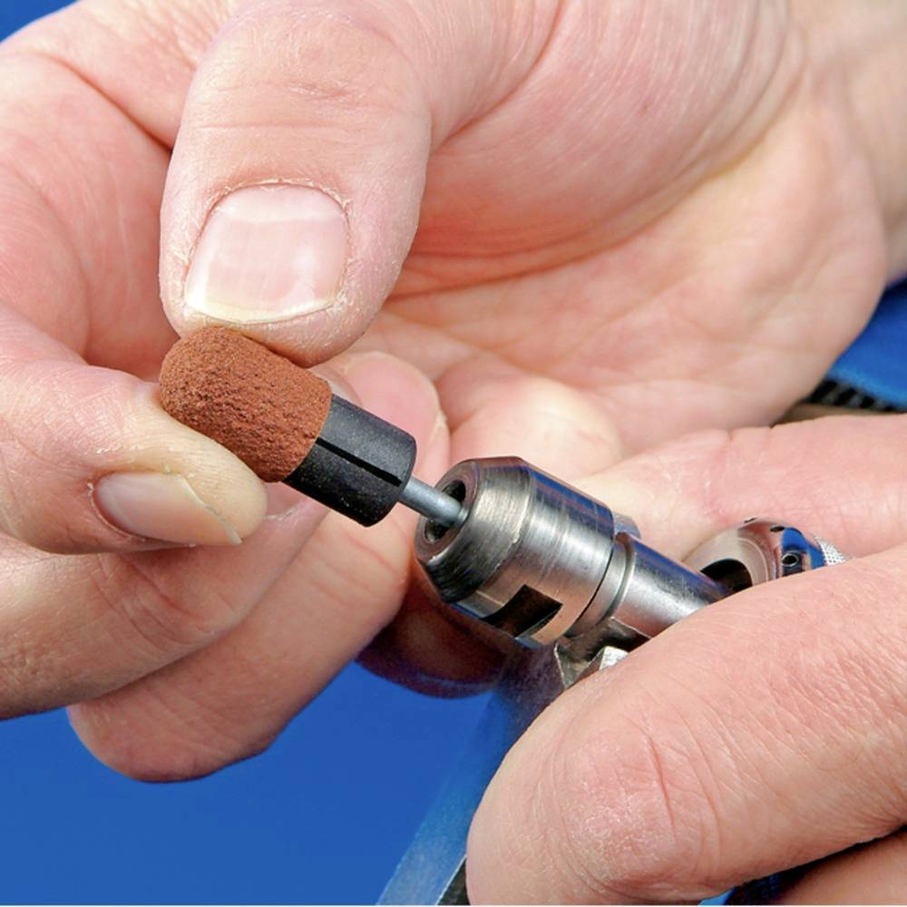 'Close-up of a hand holding a drilling tool with a brown grinding head. It is used for polishing or grinding.'