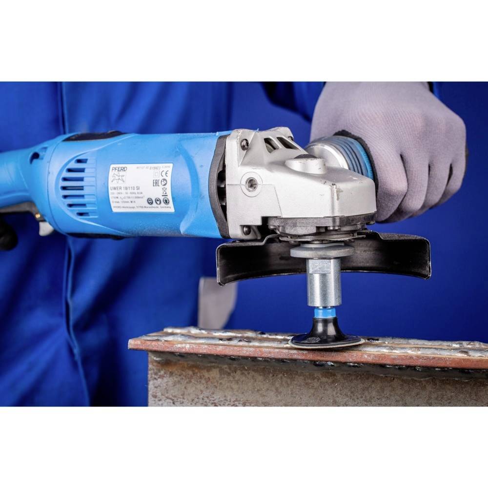 A person is holding a blue grinding machine against a metal edge. The person is wearing blue clothing and grey protective gloves.