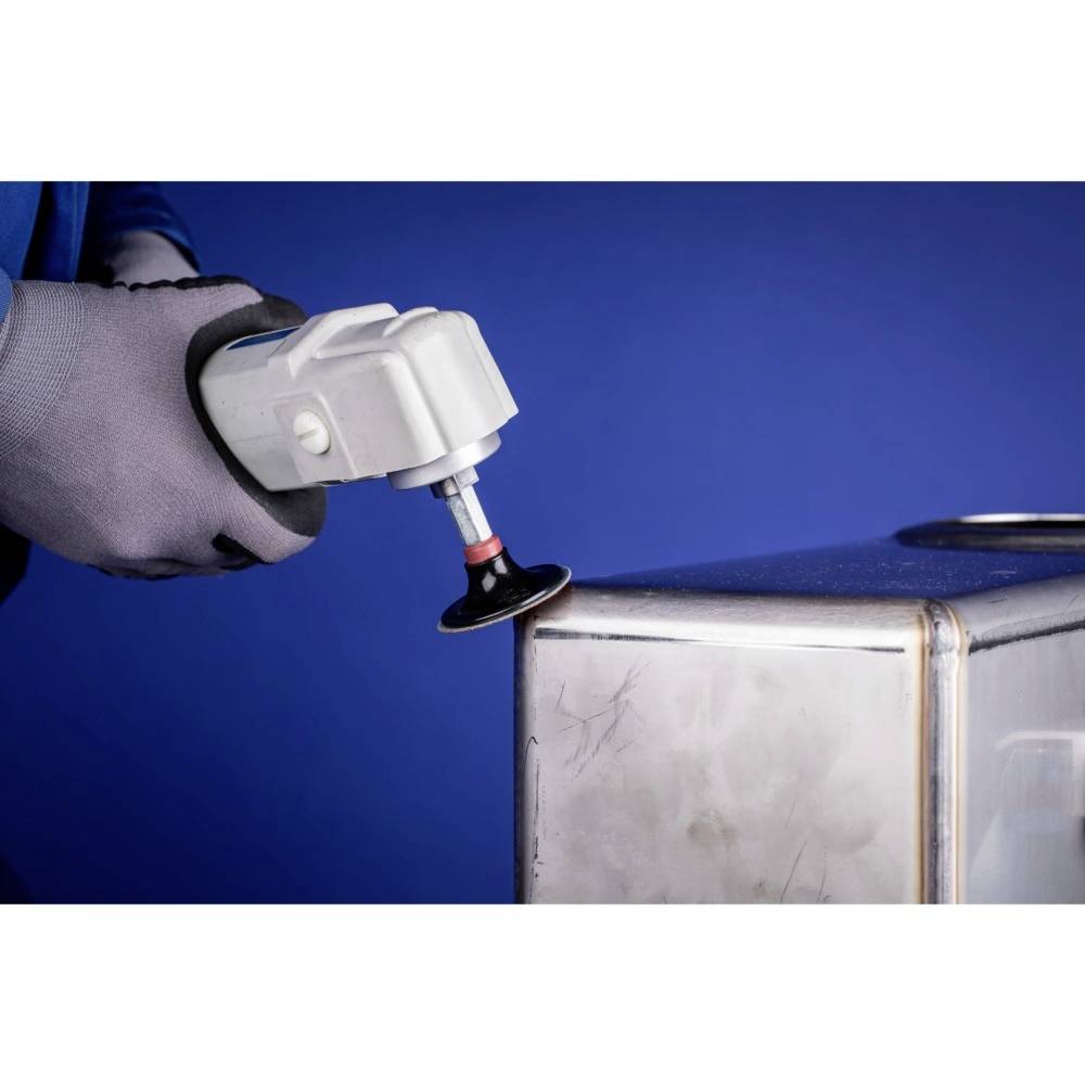 A person wearing gloves is polishing the edge of a metal object with an electric grinding tool against a blue background.