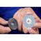 A person is holding two grinding discs of different types in their hands; on the left a black one, on the right a blue one with the inscription 'CD 50 A 180'.