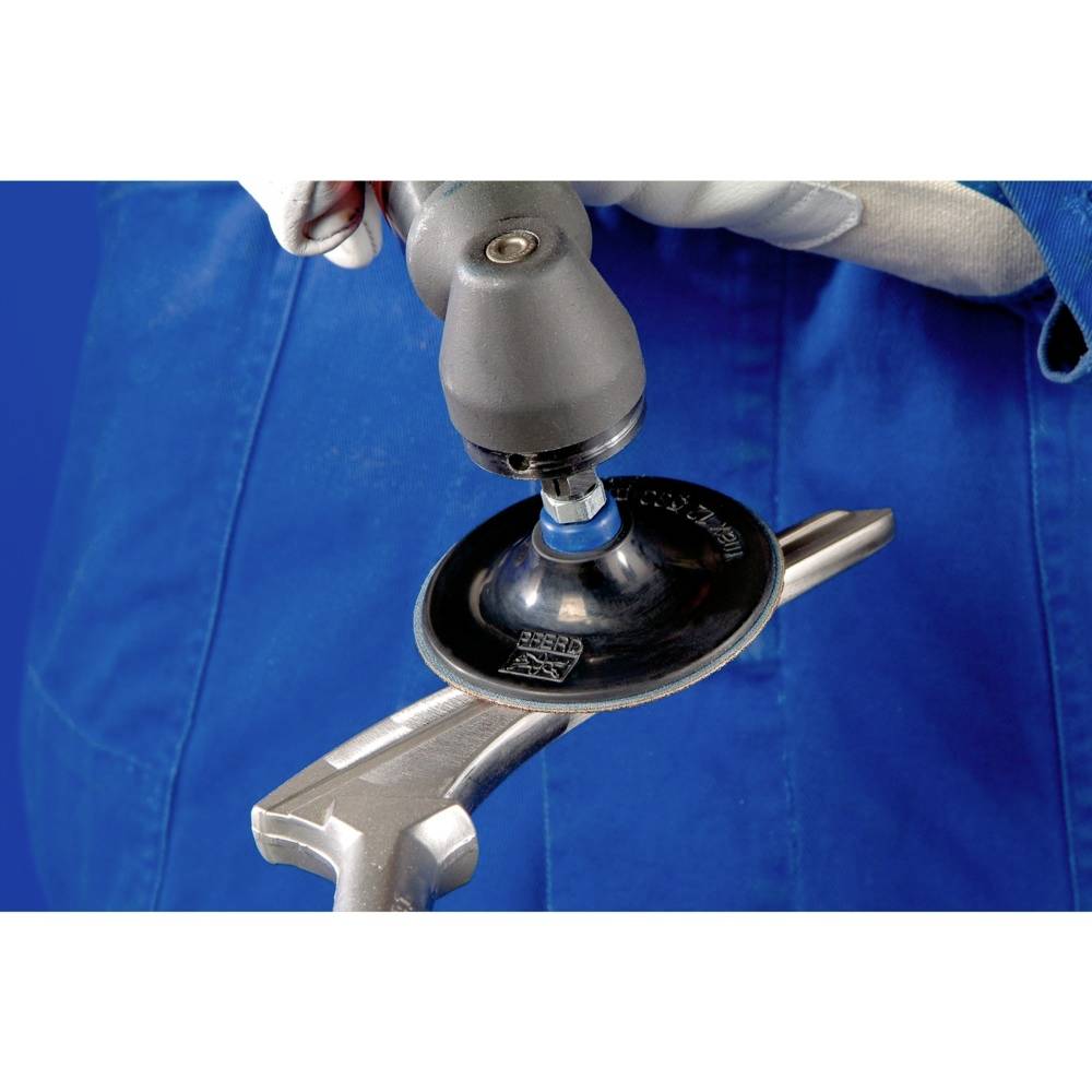 A person is grinding the handle of a spanner with an angle grinder. They are wearing blue clothing and white work gloves.