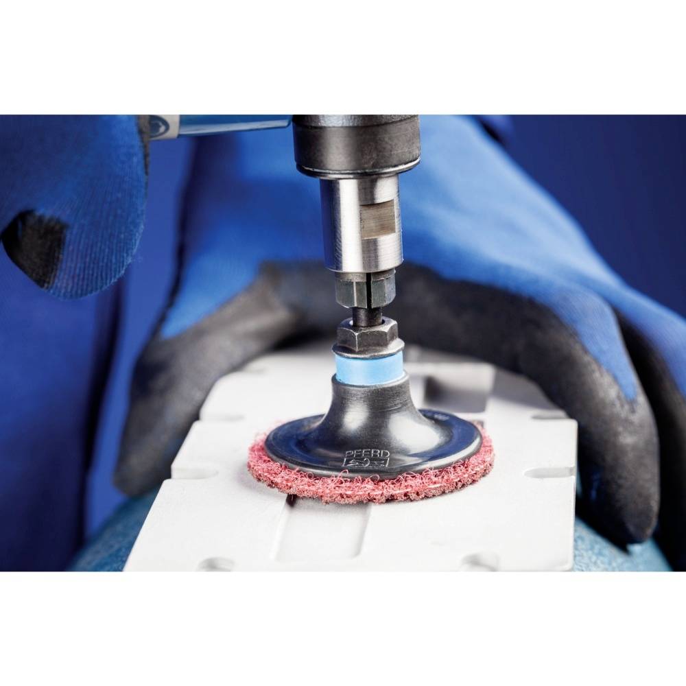 A craftsman is grinding a surface with a polishing machine. He is wearing blue gloves to ensure safety.