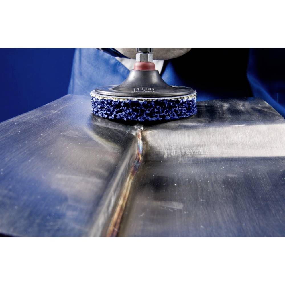 A person is polishing a metal surface with a rotating grinding wheel. The area shows a straight edge in the centre.