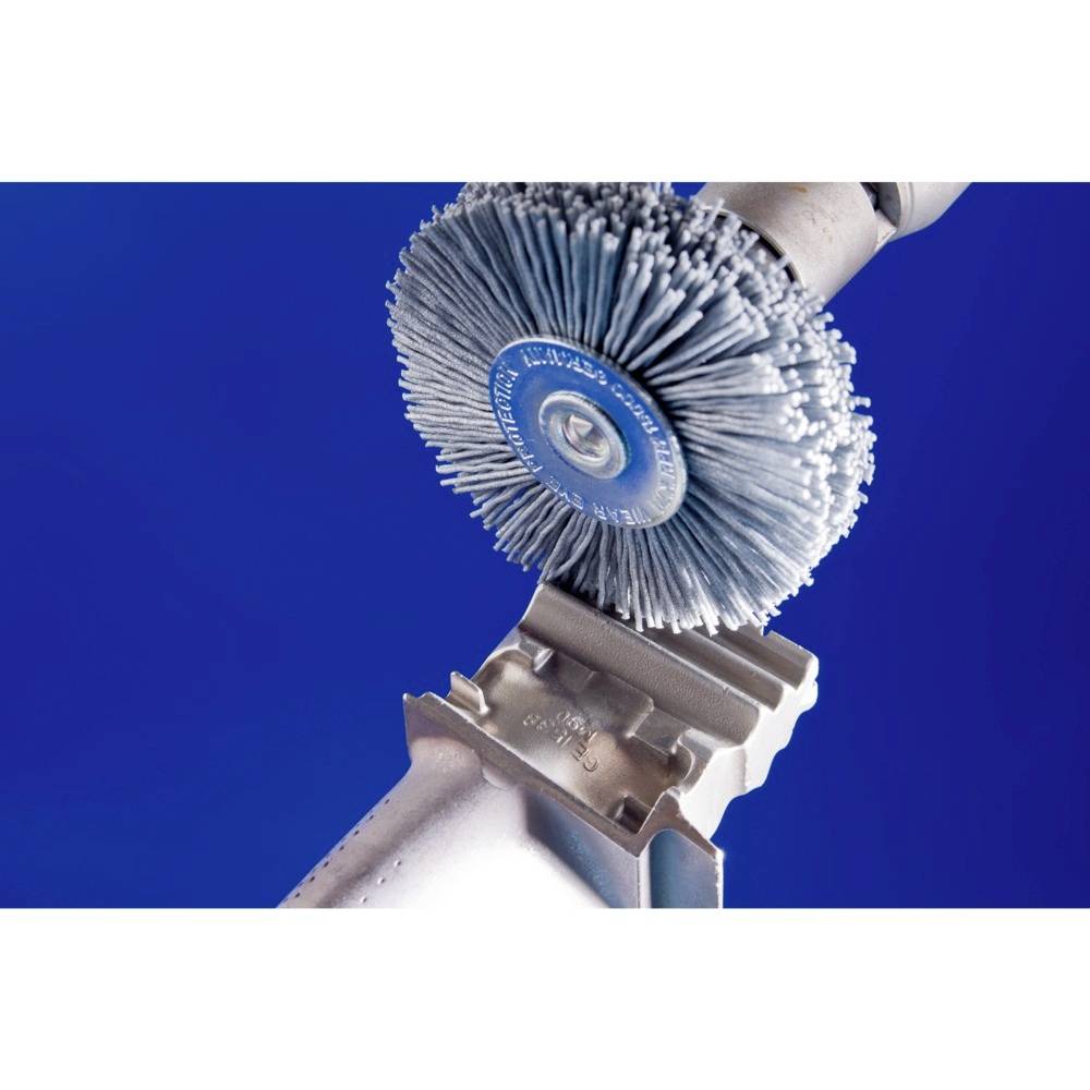 'Close-up of a rotating wire brush being applied to a metal surface, against a blue background.'