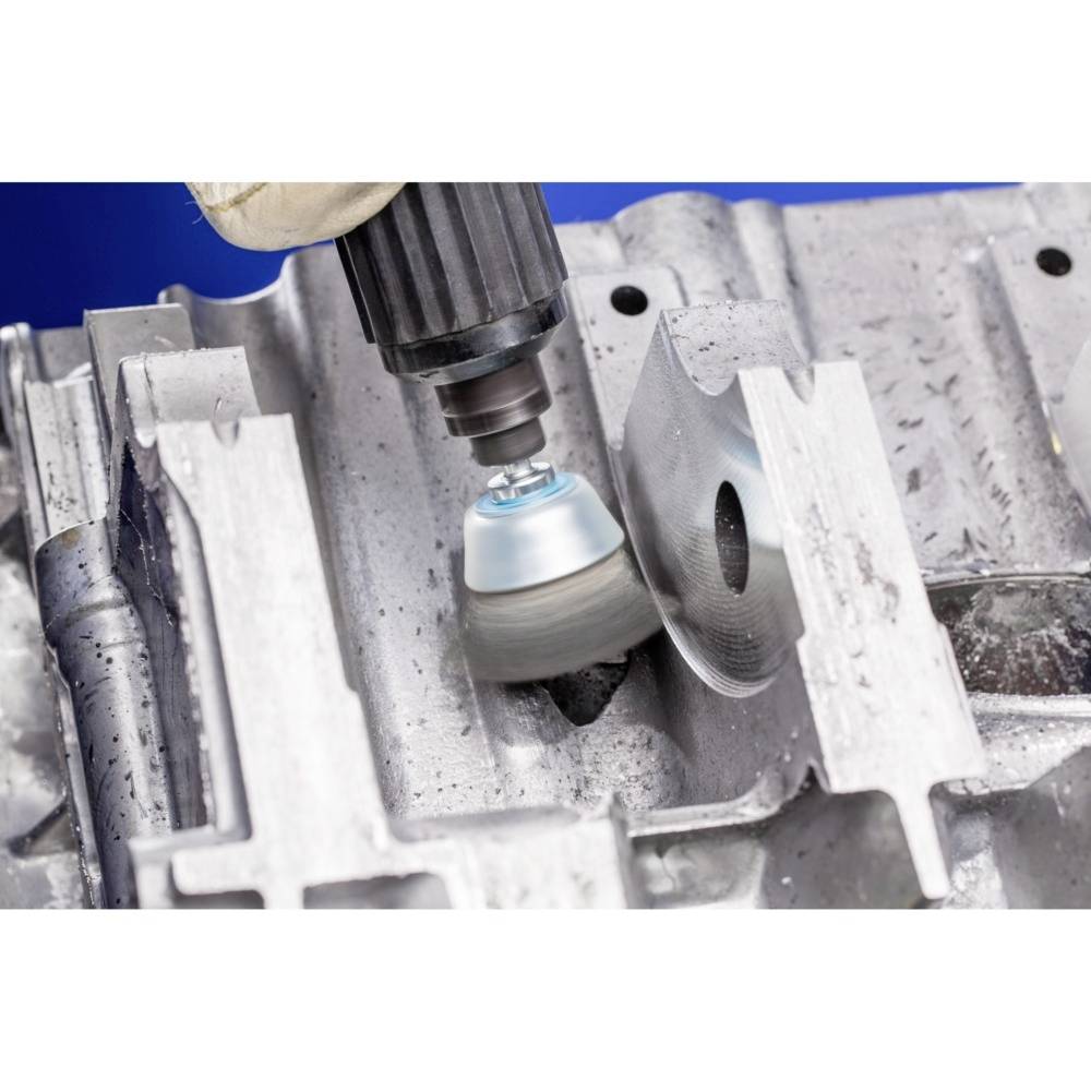 A close-up of a machine polishing a circular metal surface. The machine has a rotating brush head.