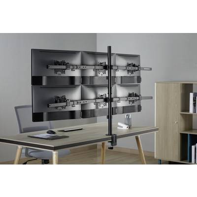 A desk clamp holds six monitor mounts, attached in two stacked rows, on a desk in an office.