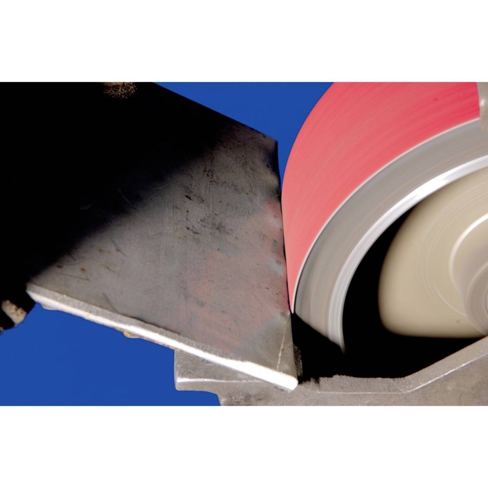 A grinding wheel is machining a metal edge. The wheel is spinning rapidly and generating sparks. The scene depicts an industrial working process.