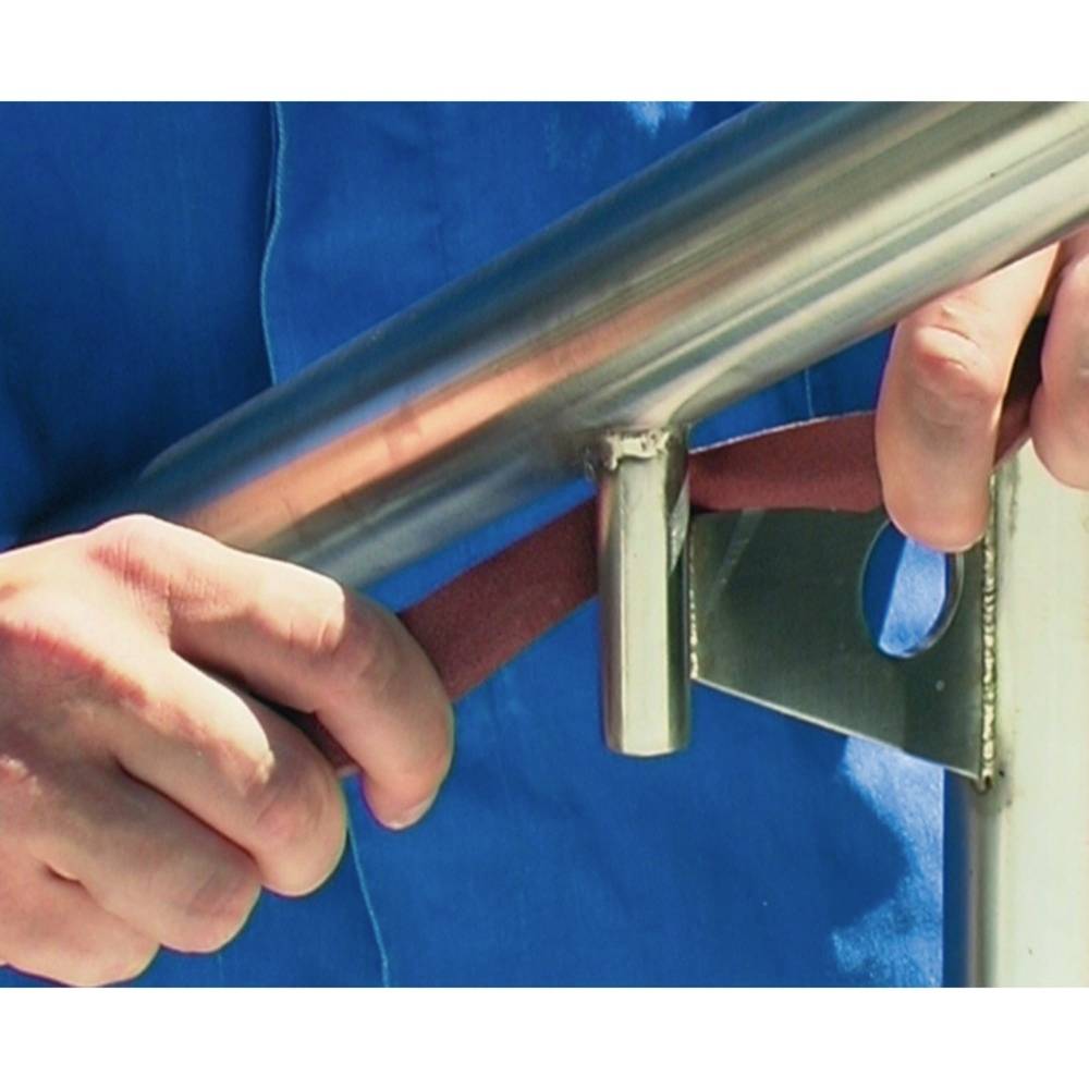 A person is wearing blue workwear and sanding a stainless steel handrail with sandpaper to smooth the surface.