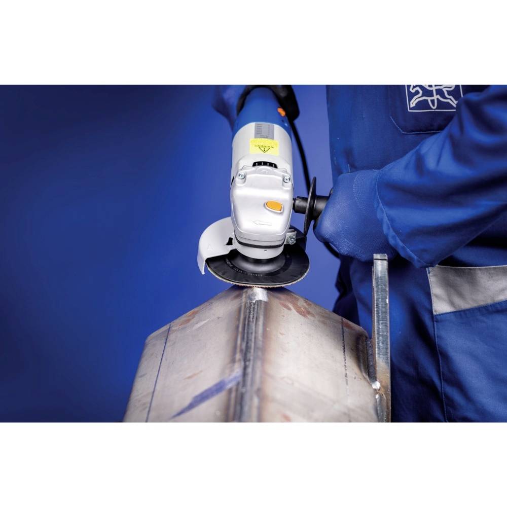 A person in blue workwear is grinding a piece of metal with an angle grinder.