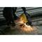 A person is cutting a metal pipe with an electric cutting machine, sparks are flying. Protective workwear is being worn.