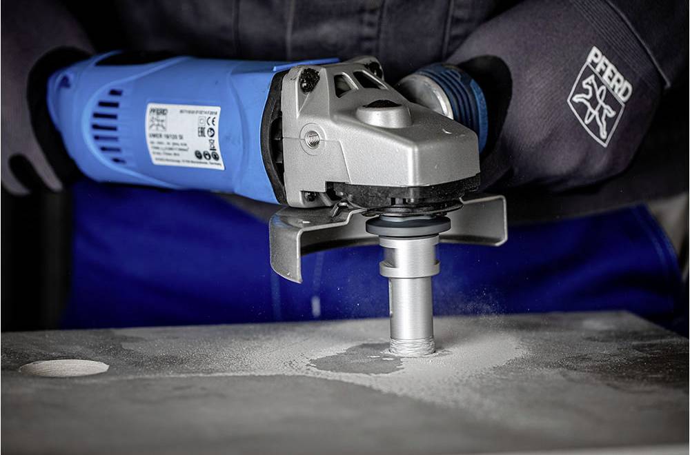 A person is using an electric tool to sand a surface. Dust is being stirred up while the device is operating.