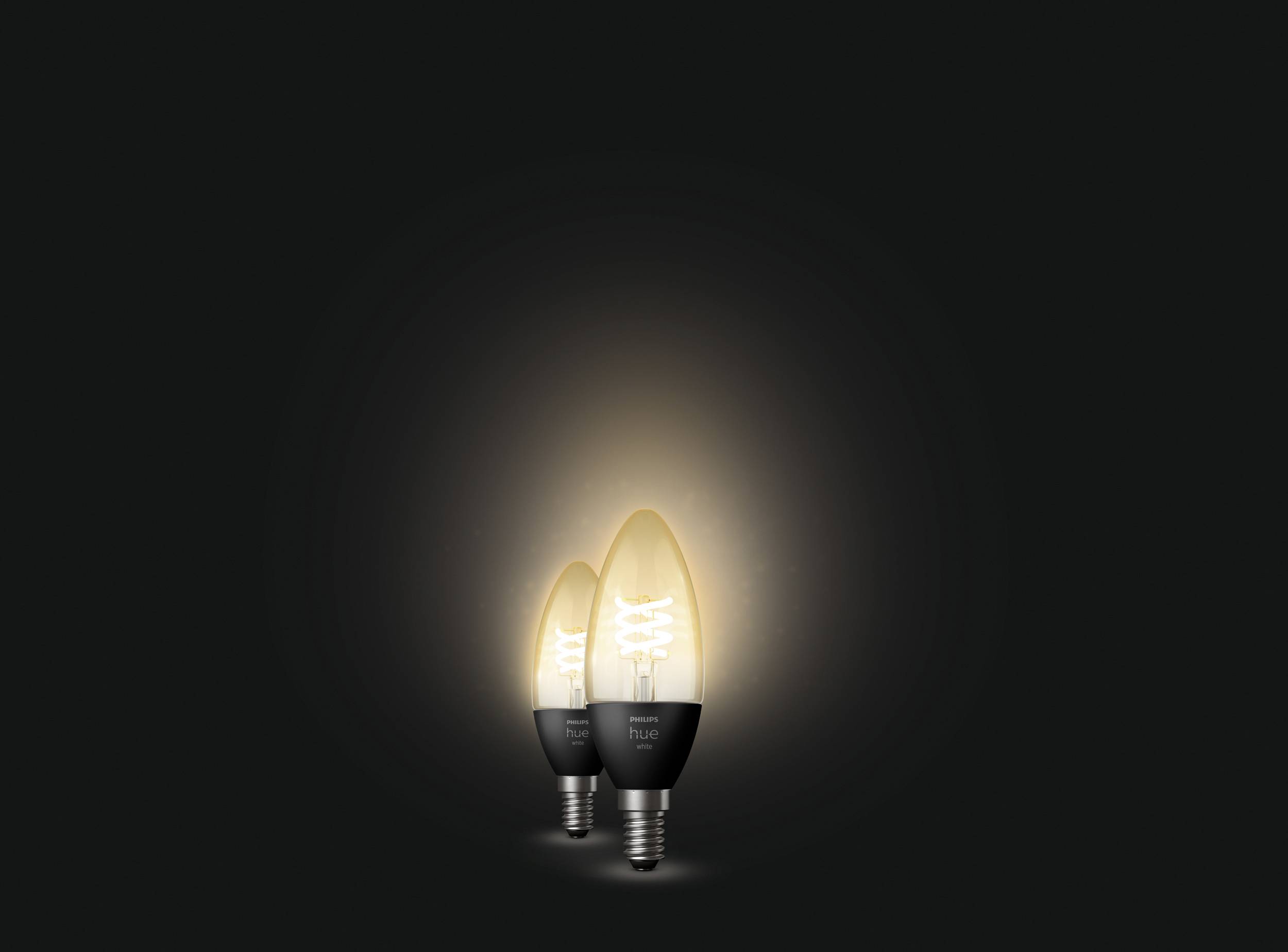 Two glowing light bulbs against a black background, different sizes, with a warm luminous glow.