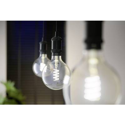 Three hanging light bulbs with visible spiral filaments glow in a dark room. Blurred window blinds are visible in the background.