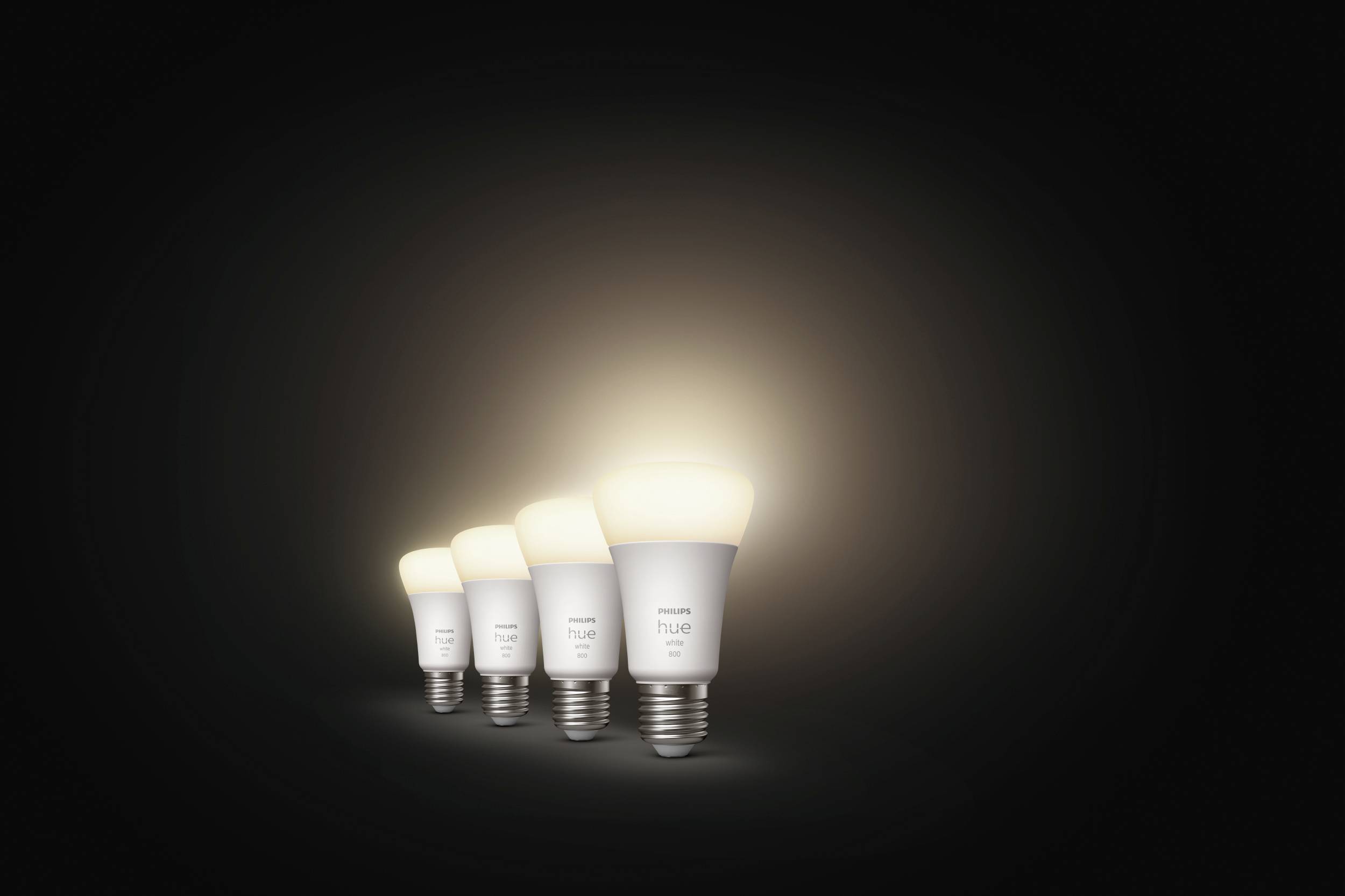 Four glowing light bulbs in a row, decreasing in size from left to right, against a black background.
