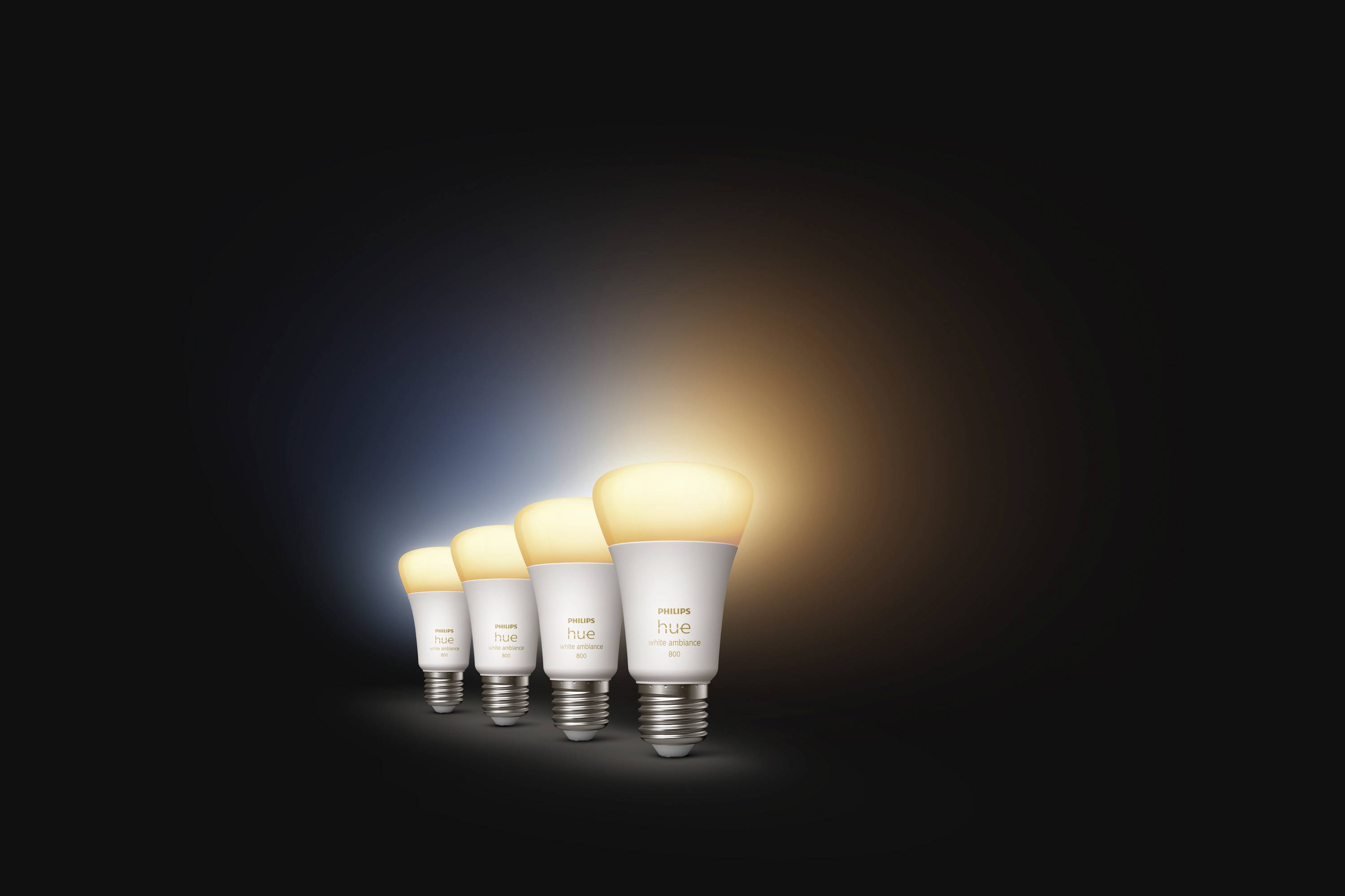 Four intelligent LED light bulbs side by side, glowing in warm, yellow light.