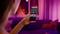 A person is using a smartphone in a atmospherically lit room. Several apps are visible on the screen.