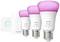 'Philips Hue White and Color Ambiance E27 LED Bulbs' in three sizes in front of a wireless dimmer switch. Bulbs are illuminated in pink.