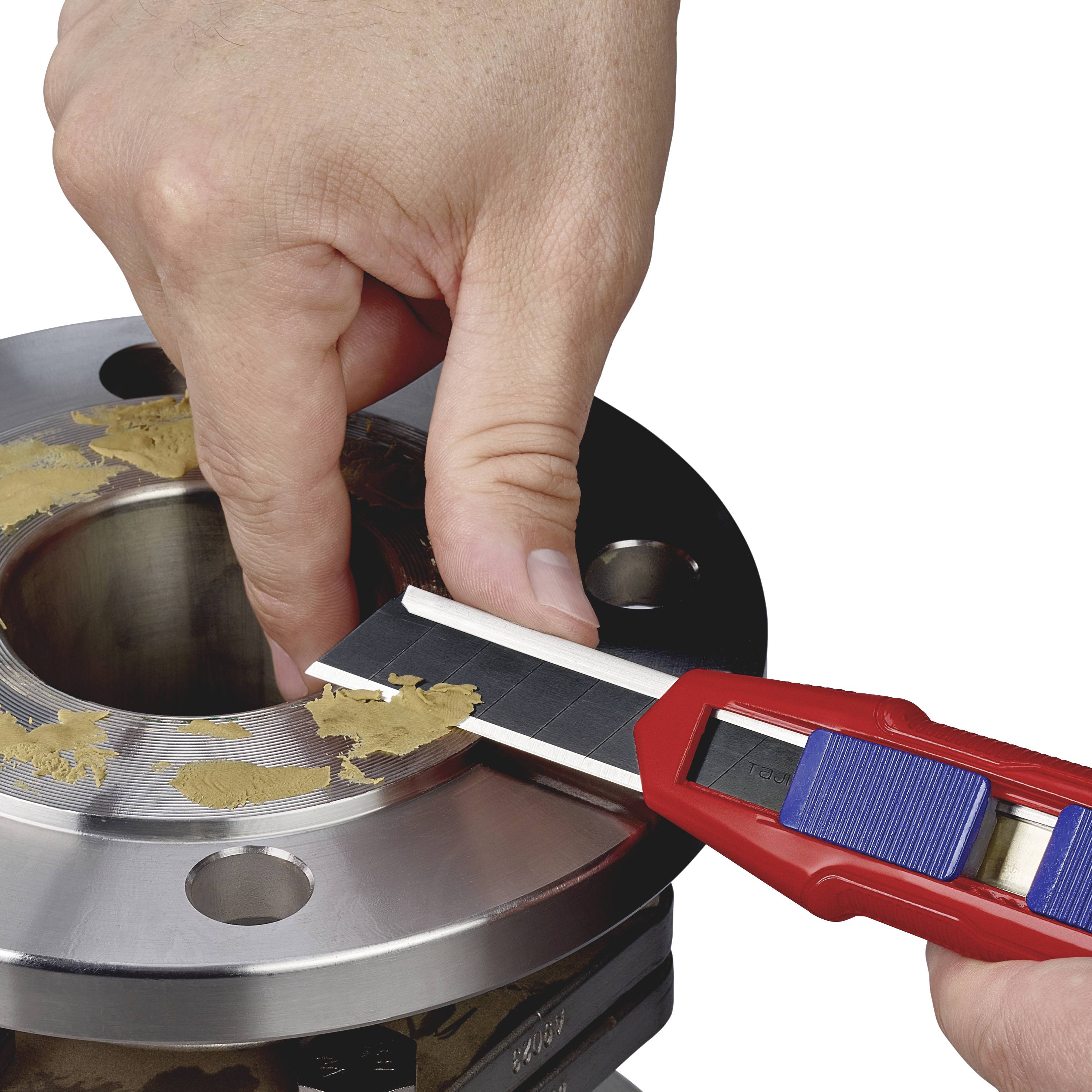 A hand removes sealing material from a metallic, cylindrical surface with screw holes using a red scraper.