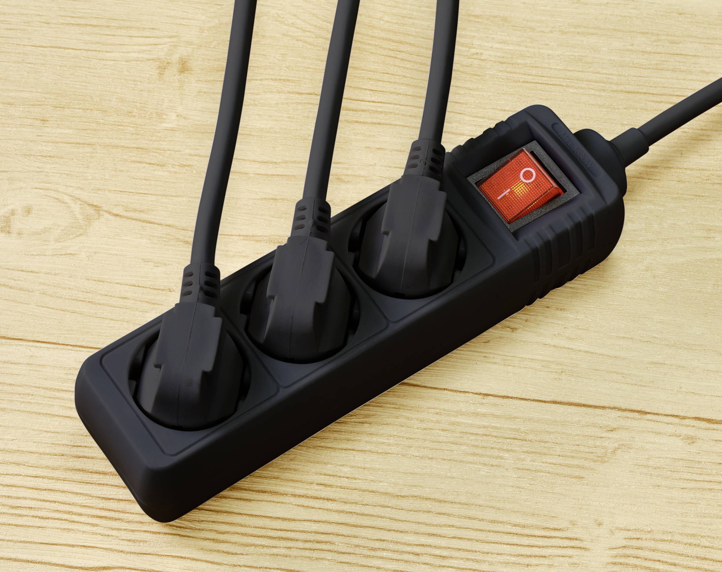 A black power strip with three black cables plugged in is lying on a wooden table. The switch is set to 'Off'.