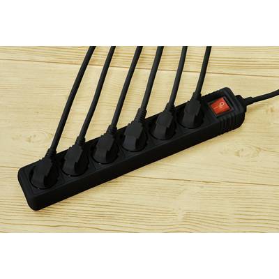 A black multi-socket adaptor with six connected power cables and a red toggle switch lying on a wooden table.