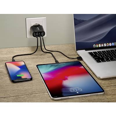 A laptop, a tablet and a smartphone are connected to a charger in a plug socket with cables.