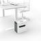 A shredder sits under an office desk next to a swivel chair, ready for secure document disposal in the office.