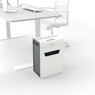 A paper shredder stands next to a desk with an office chair. The room appears to be furnished in a modern and minimalist style.