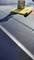 A wax container and a yellow cloth lie on a car surface covered with water droplets, ready for car care.