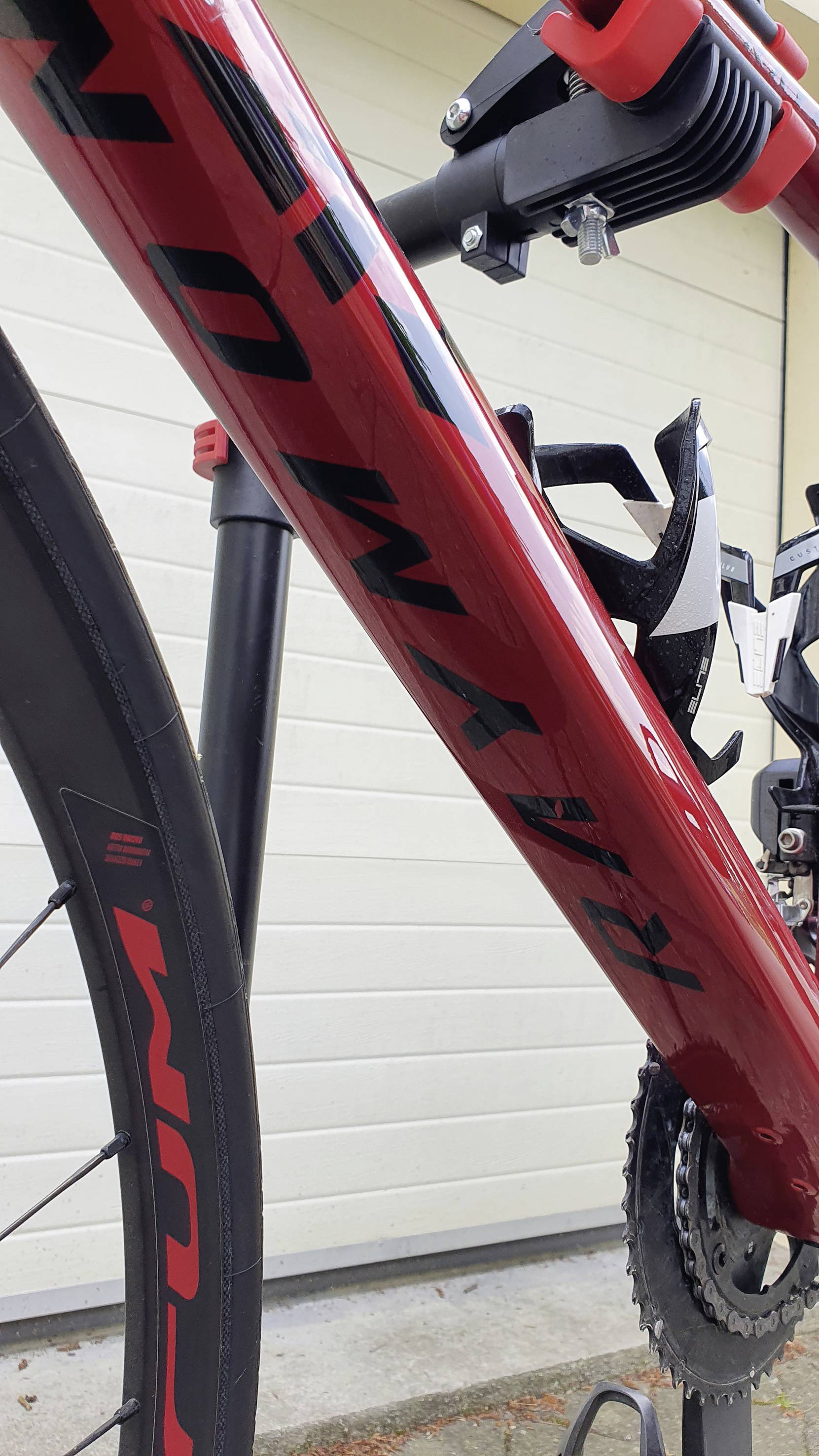 A red racing bicycle is standing on a bike rack in front of a white wall.