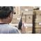 A person is holding a two-way radio and standing in front of stacked boxes, possibly in a warehouse.