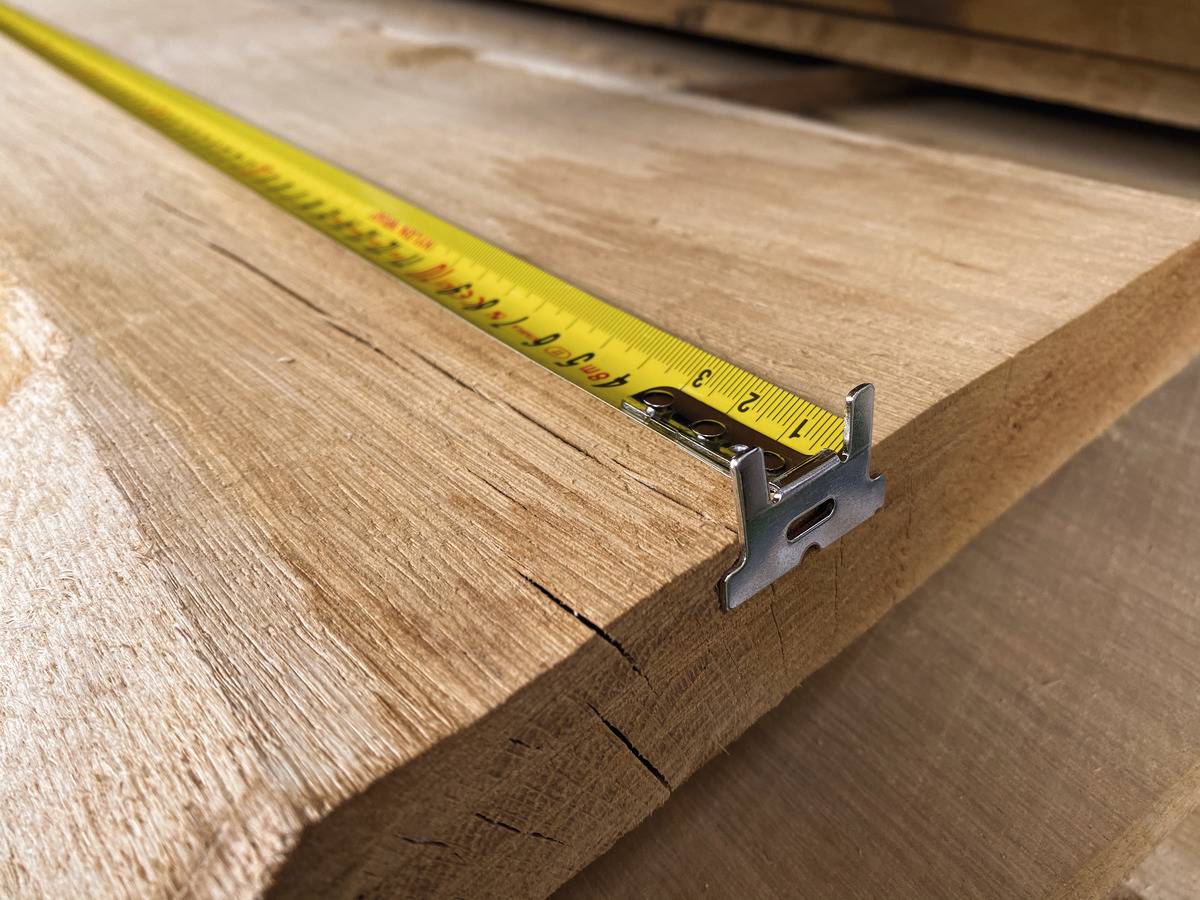 A yellow tape measure lies on a wooden board and indicates a length of approximately 36 centimetres.