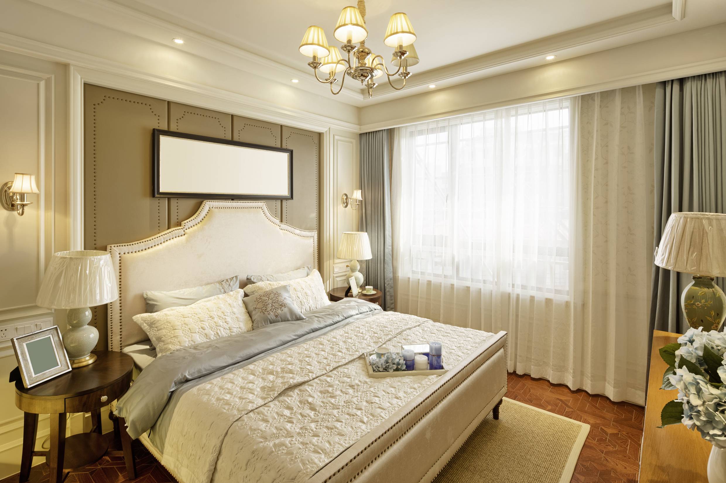 An elegant bedroom with a large bed, two bedside tables with lamps and a window with curtains that let in daylight.