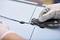 A person wearing gloves cuts through a cable tie with a knife, separating two grey plates.
