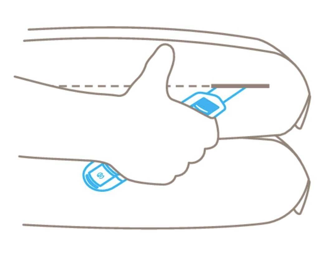 Thumb pointing upwards between two cushions. Objects or symbols are visible on the cushions.