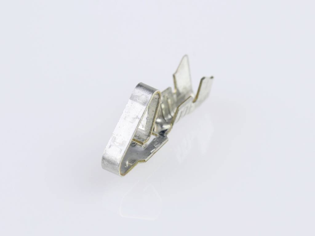 A single metal clip with a reflective surface lies on a light-coloured background.