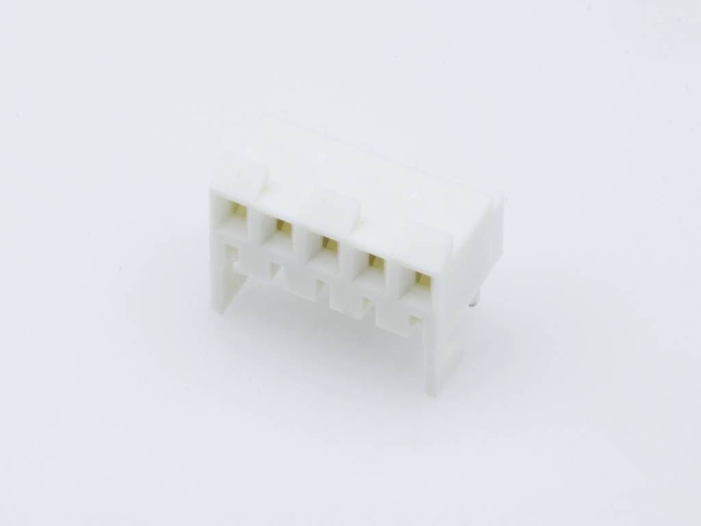 A white, rectangular plastic plug lies on a white surface. The plug has five connections in a row.