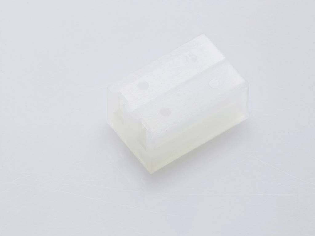 A translucent, rectangular plastic block with two vertical holes, placed on a white surface.