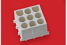 White, square plastic block with nine round openings on a red background.