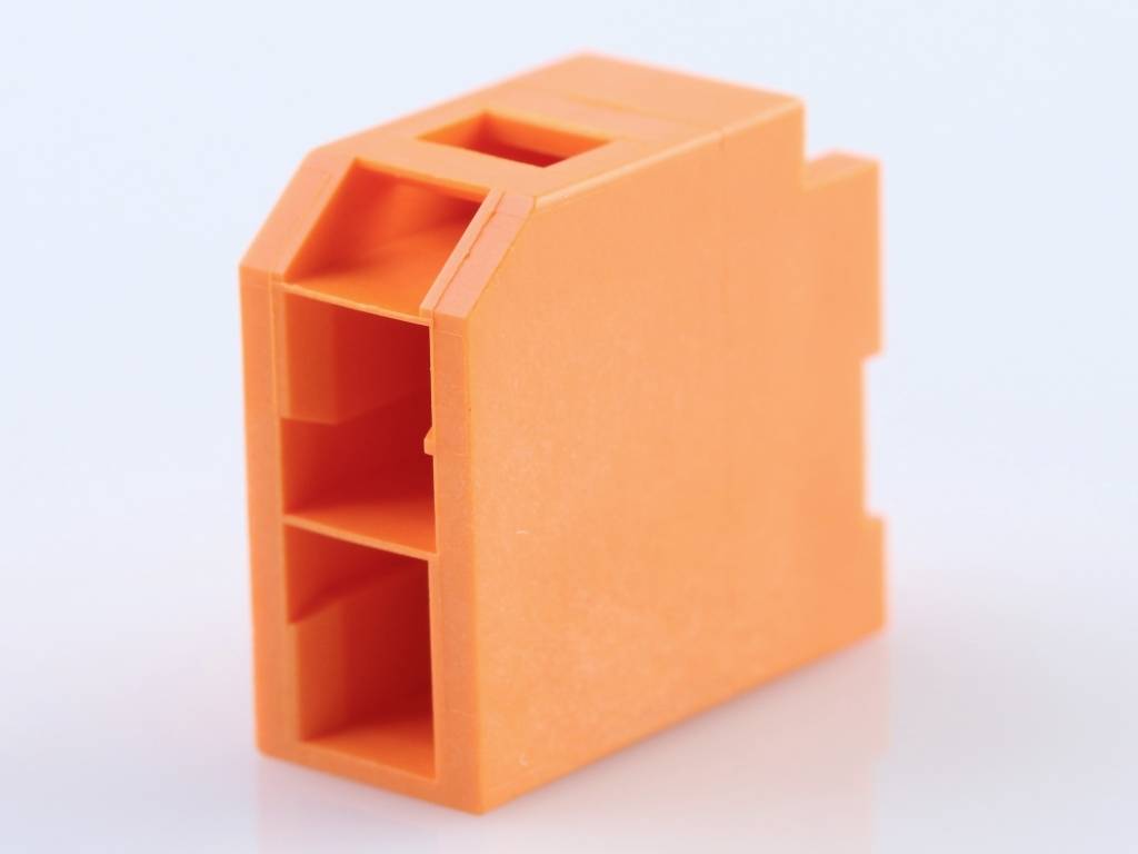 An orange plastic block with rectangular cutouts and a bevelled top edge, potentially a component.