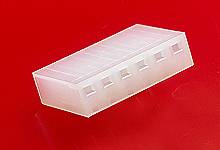 A transparent, rectangular plastic plug with multiple square openings, against a red background.