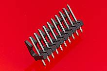 A black connector with multiple pins is placed diagonally on a red surface.